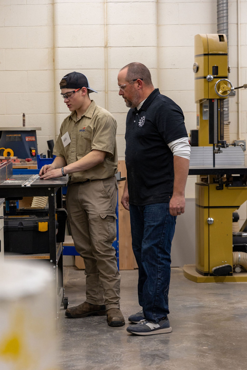 Slinger HS SkillsUSA Advisor, Mr Kolpack, assists a cabinetmaking contestant
