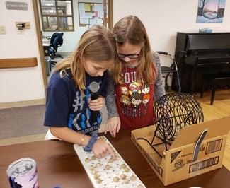 Two girls putting bingo balls into their block