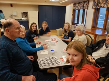Students and senior citizens playing bingo at a table