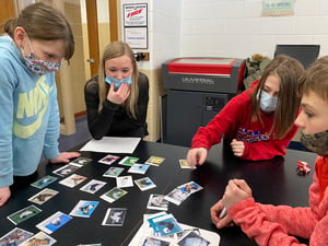 Students review cards on a classroom table