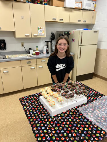 Smiling girl standing by group of homemade cake pops