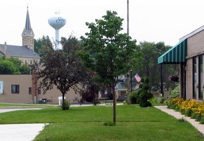 Downtown Slinger image with view of water tower, green grass and trees and U.S. flag flying